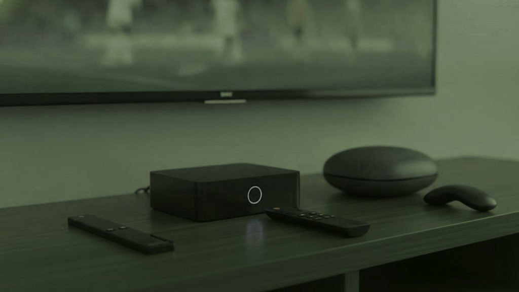 Clé de streaming, boîtier TV et boîtier rond avec leurs télécommandes sur un meuble TV