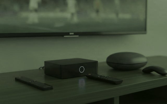 Clé de streaming, boîtier TV et boîtier rond avec leurs télécommandes sur un meuble TV