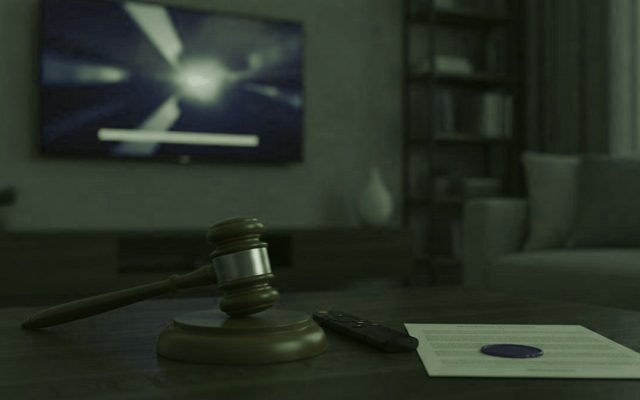 Marteau de juge, télécommande de streaming et document scellé sur une table basse devant un téléviseur
